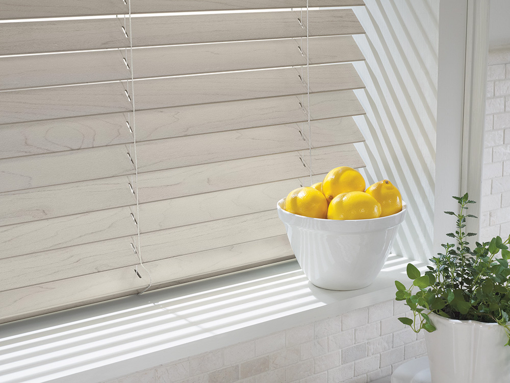 Close up of custom made faux wood blinds with a bowl of lemons sitting on the window sill.